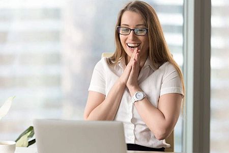 excited woman sitting in front of a pc
