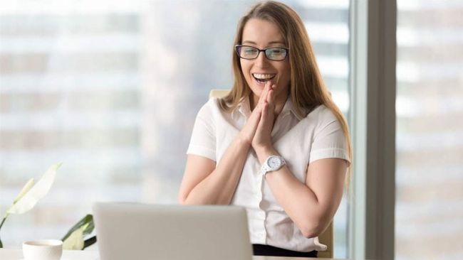excited woman sitting in front of a pc